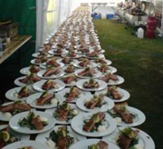 An enormous table lined with hot smoked salmon starters ready to serve